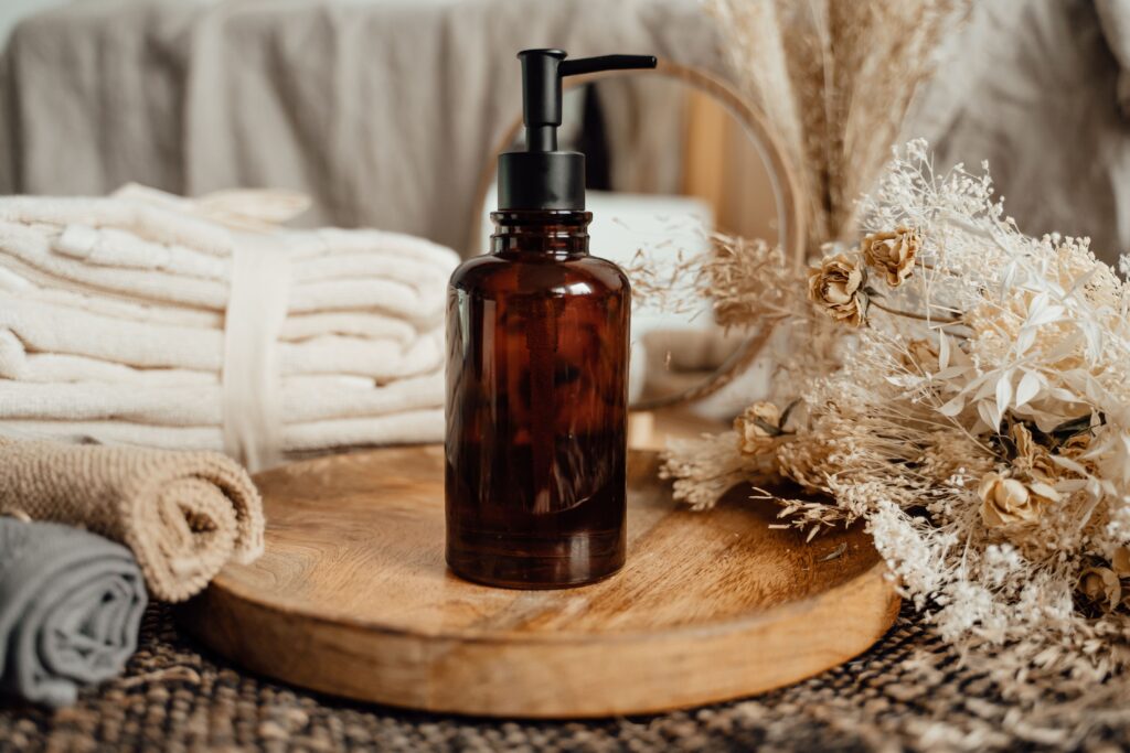 services-03 A beautifully arranged skincare setup with a glass bottle, towels, and dried flowers on a wooden tray, perfect for spa imagery.
